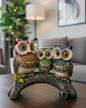 Three owl figurines on a branch in a living room setting